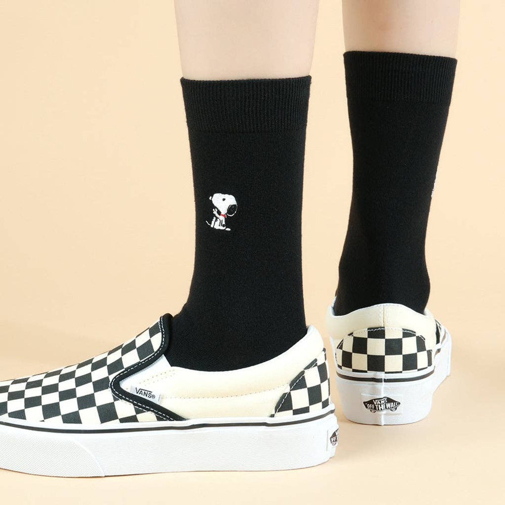 Three pairs of socks with cartoon Snoopy characters in a box, surrounded by more boxes. The perfect gift for snoopy lovers