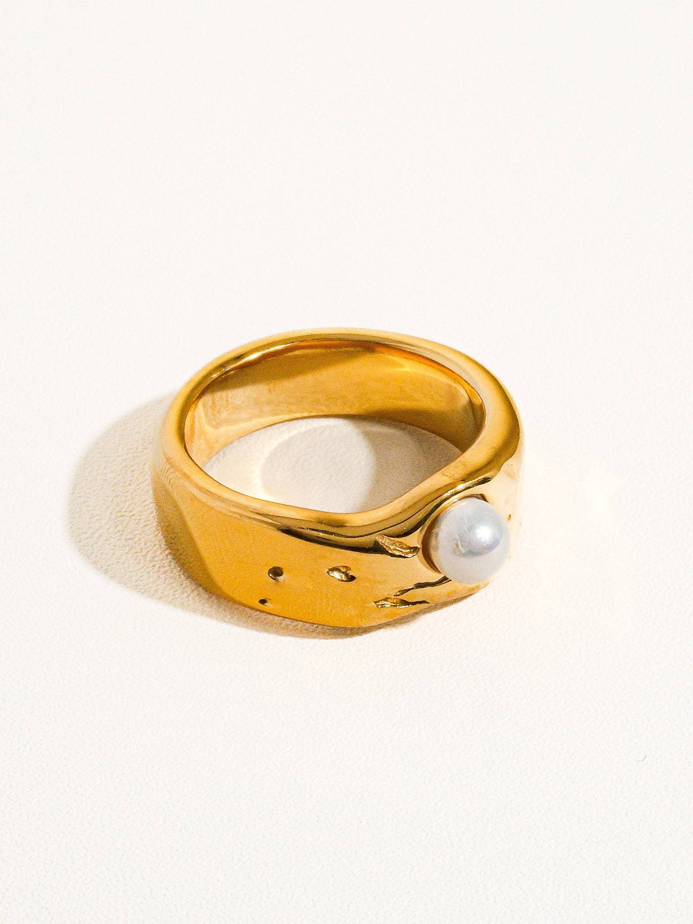 Gold ring with a pearl on a white background