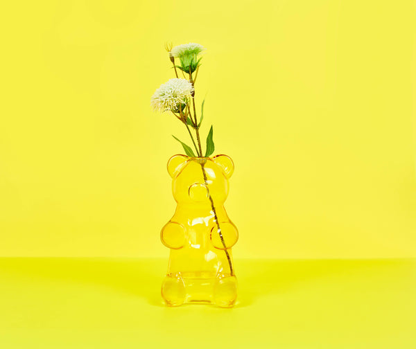 Yellow gummy bear-shaped vase with flowers on a yellow background