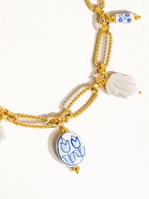 Gold chain bracelet with ceramic tulip charms on a white background