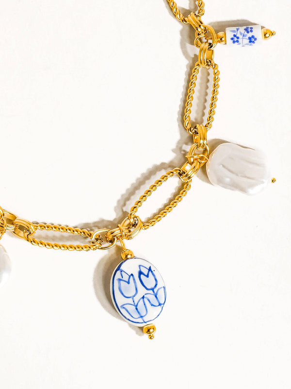 Gold chain bracelet with ceramic tulip charms on a white background