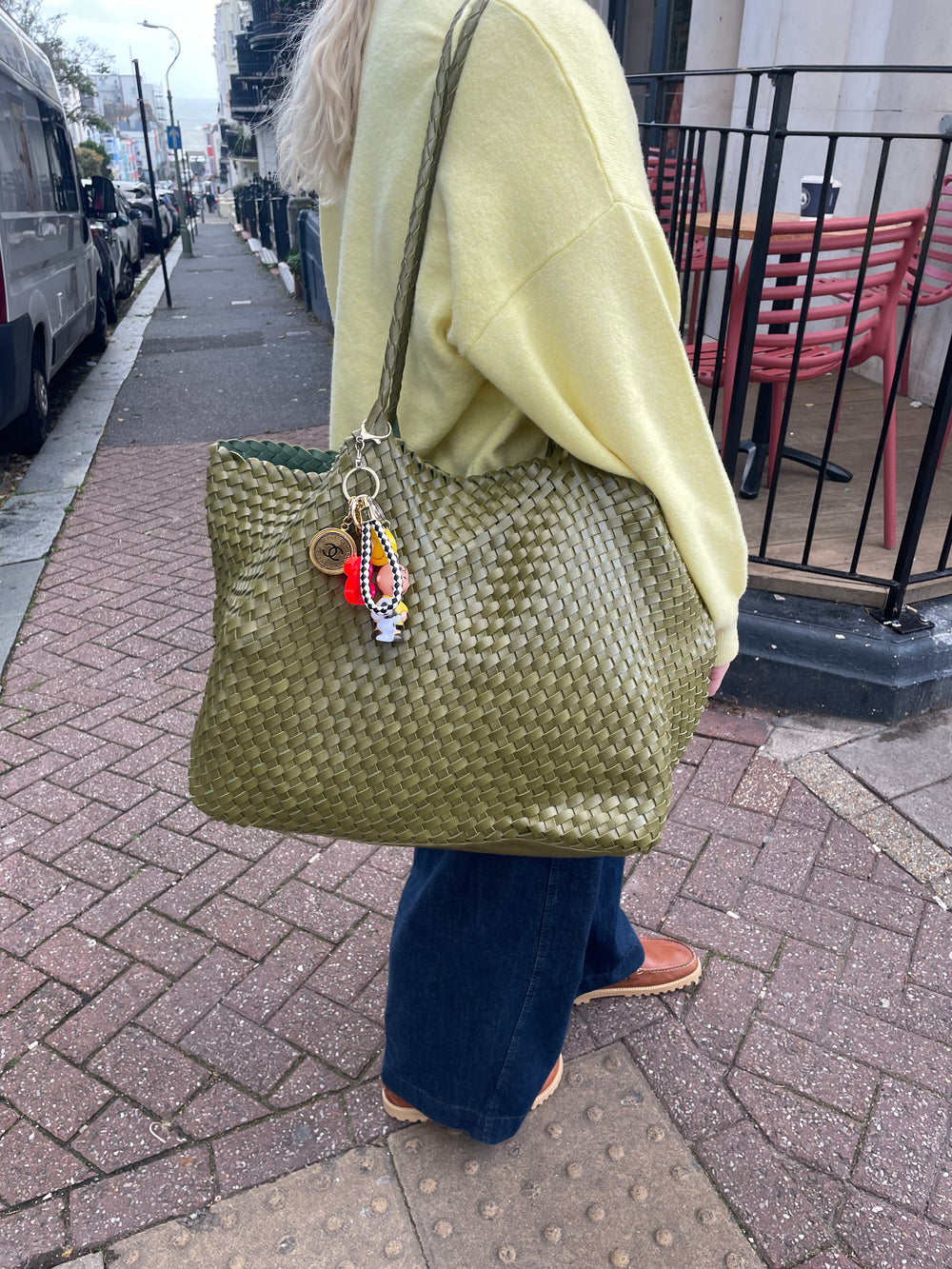 Person holding a black woven handbag on a pavement
