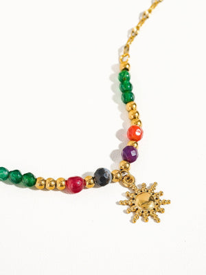 Colorful beaded bracelet with a sun charm on a white background