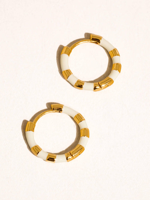 Pair of gold and white hoop earrings on a white background