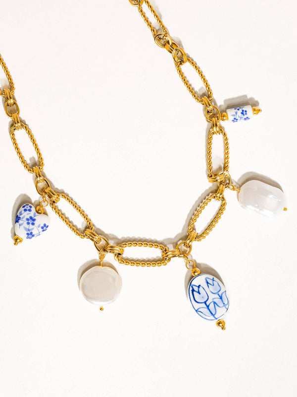Gold chain necklace with ceramic charm pendants on a white background